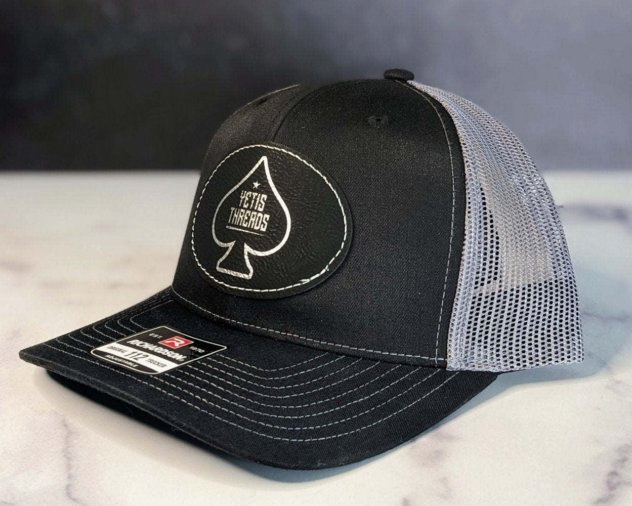 Side Angle of Yeti's Thread patch on a Black and Charcoal Hat.