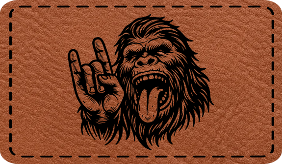 Close-up of the 'Bigfoot Rock Out' leatherette patch, featuring Bigfoot throwing rock horns with his tongue out, perfect for Sasquatch and music fans.